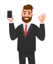 Happy successful businessman showing smart phone, mobile, cell phone in hand and gesturing okay or OK sign. Good, deal, agree. Royalty Free Stock Photo