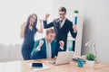 Happy successful businesspeople triumphing with raised hands and looking at laptop Royalty Free Stock Photo