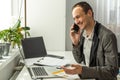 Happy successful busy caucasian man in a suit, company employee, top manager, boss, sitting in the office, talking on