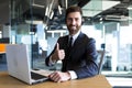 Happy and successful call center employee looks at the camera and smiles, businessman keeps his finger approvingly up, working at Royalty Free Stock Photo