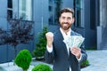 Happy successful Caucasian bearded businessman counts, waves, throws, show off, flaunt cash money background a modern office Royalty Free Stock Photo