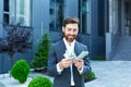 Happy successful Caucasian bearded businessman counts, waves, throws, show off, flaunt cash money background a modern office Royalty Free Stock Photo