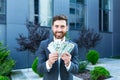 Happy successful Caucasian bearded businessman counts, waves, throws, show off, flaunt cash money background a modern office Royalty Free Stock Photo