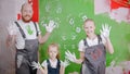 Happy successful family are putting their white handprints on a green wall - looking in the camera Royalty Free Stock Photo