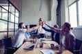 Happy successful multiracial business team giving a high fives gesture as they laugh and cheer their success.