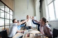 Happy successful multiracial business team giving a high fives gesture as they laugh and cheer their success. Royalty Free Stock Photo