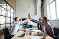 Happy successful multiracial business team giving a high fives gesture as they laugh and cheer their success.