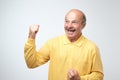 Happy successful pensioner or business man winning, fists pumped celebrating success grey wall background. Royalty Free Stock Photo