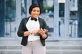 Happy successful professional posing near office building. Young African American business woman standing outside. Female business