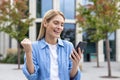 Happy successful winner woman in blue casual shirt received online notification message on phone, mature business woman Royalty Free Stock Photo