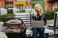 Happy and successful woman working with laptop on a bench while her little child Royalty Free Stock Photo