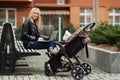 Happy and successful woman working with laptop on a bench while her little child Royalty Free Stock Photo