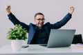 Happy successful young business man cheering with clenched fists in office Royalty Free Stock Photo