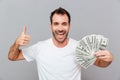 Happy successful young man holding money and showing thumbs up Royalty Free Stock Photo