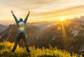 Hiking Man with Backpack jumping with raised arms on mountain. Amazing sunrise Backlight with beautiful lens flares and Royalty Free Stock Photo