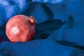 Happy Sukkot, New Year, Shanah Tovah concept : Pomegranate alone on blue cloth texture background with sharp light, strong shadows
