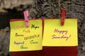 Happy Sunday greeting note concept on sticky notes with colorful positive single word written on yellow paper, hanging on wood. Royalty Free Stock Photo