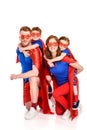 happy super parents piggybacking adorable smiling kids in masks and cloaks