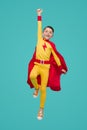 Happy superhero kid jumping with raised arm