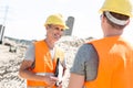 Happy supervisor discussing with colleague at construction site