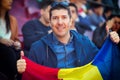 Happy supporter holding Romanian national flag in hands at international sport event Ã¢â¬â man in the stands of stadium cheering Royalty Free Stock Photo