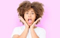 Happy suprised shocked excited girl face with afro curly hair. Young dark skin woman isolated on pink background. African american