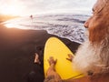 Happy surfer senior sitting on surfboard watching sunset time - Mature bearded man having fun on surfing day Royalty Free Stock Photo