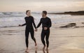Happy surfers couple holding hands while running together on the beach Royalty Free Stock Photo