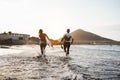 Happy surfers running in the water at sunset time - Young couple having fun surfing in ocean Royalty Free Stock Photo