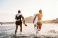 Happy surfers running in the water at sunset time - Young couple having fun surfing in ocean Royalty Free Stock Photo