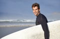 Happy, surfing and portrait of man on beach with surfboard for waves on summer vacation, weekend or holiday by sea Royalty Free Stock Photo