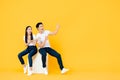 Happy surprised attractive Asian couple pointing and looking at blank space beside in yellow isolated stuidio background