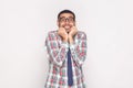 Happy surprised bearded businessman in colorful checkered shirt, blue tie and black eyeglasses standing, touching face and Royalty Free Stock Photo