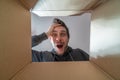 Happy and surprised man is opening a gift and looking inside cardboard box. Royalty Free Stock Photo