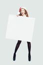 Happy surprised woman fashion model in black tights, high heels shoes and Santa hat holding empty paper banner Royalty Free Stock Photo