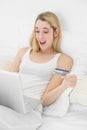 Happy surprised woman home shopping with her laptop lying on her Royalty Free Stock Photo