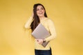 Happy surprised woman in yellow sweatshit hold laptop. Portrait of pretty woman on yellow background. Pantone