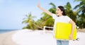 Happy and surprised young asian woman traveler with yellow suitcase at beach vacation background with palm tree and ocean. Royalty Free Stock Photo
