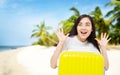 Happy and surprised young asian woman traveler with yellow suitcase at beach vacation background with palm tree and ocean. Copy Royalty Free Stock Photo