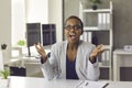 Happy surprised black woman sitting at office desk, looking at camera and applauding Royalty Free Stock Photo