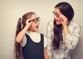 Happy surprising mother and excite kid in fashion glasses looking each other with opened mouth on empty copy space background. Vi