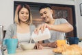 Happy sweet Asian couple having breakfast, cereal in milk, bread and drinking orange juice after wake up in the morning.