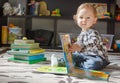 Happy sweet baby boy reading books sitting on the floor, at home