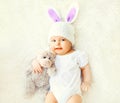 Happy sweet baby in knitted hat with a rabbit ears and teddy bear toy