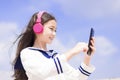 Happy syudent girl  listening music in headphones, holding mobile phone Royalty Free Stock Photo