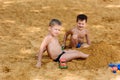 Happy tanned children play in yellow sand