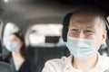 A happy taxi driver wearing a mask and the passenger on the back seat of the car Royalty Free Stock Photo