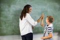 Happy teacher and school boy giving high five in classroom Royalty Free Stock Photo
