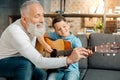 Loving grandfather teaching grandson how to hold guitar Royalty Free Stock Photo