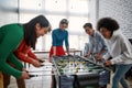 Happy team. Group of young and excited multicultural people in casual wear playing table soccer in the modern office and Royalty Free Stock Photo